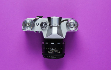 Vintage retro film camera on purple background. Top view