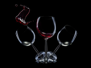 Obraz na płótnie Canvas Set of empty glasses for red wine with splashes in a row isolated on black background.