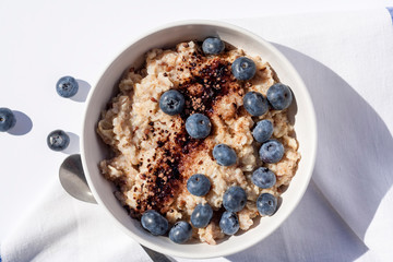 Oatmeal with blueberies and cocoa powder in a round bowl, Close. Top view.