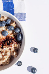 Oatmeal with blueberies and cocoa powder in a round bowl, Close. Top view.