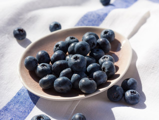Ripe blueberries on a pink small plate on a white and blue napkin. Close.