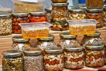 Lots of assorted honey on the table. Jars of sweets are sold at the fair. Honey with different kinds of nuts then dried fruits.
