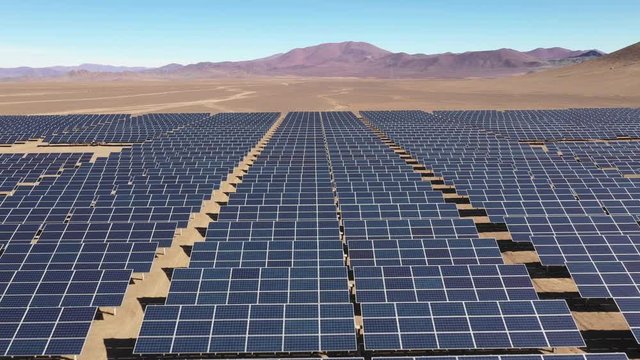 Aerial footage hundreds solar energy modules or panels rows along the dry arid lands at Atacama Desert, Chile. Huge Photovoltaic PV Plant in the middle of the desert from an aerial drone point of view