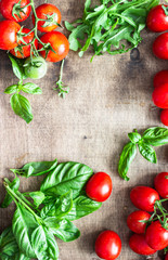 Fresh ripe cherry tomatoes and basil on a wooden background.