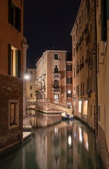 Fototapeta na wymiar Stunning landscape of Venice at night. Long exposure photo of calm landscape of the city. Small boat in a calm canal at nighttime.