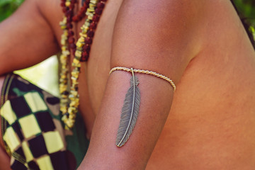 Dark skin male body part with fashionable metal feather bracelet