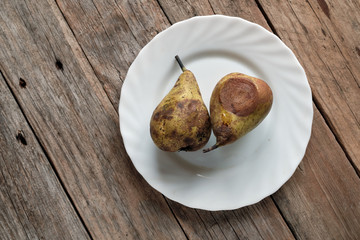 Two rotten pears on a white plate