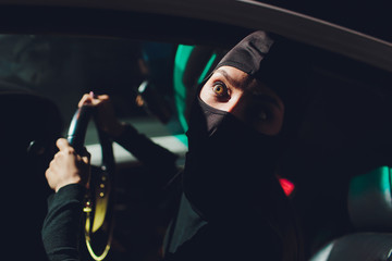 Masked robber woman car The thief is levering the lock at the door car robbery.