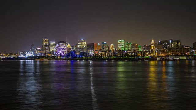 Night time lapse of Montreal old port with the Saint Lawrence river and a ferris wheel, Zoom out