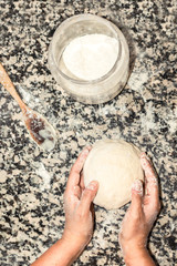 Top view of hands chef preparing a big ball of dough with flour on kitchen marble board. Preparing and kneading dough to cooking bread or pizza.
