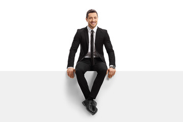 Young man in a suit sitting on a panel and smiling