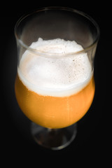 One single glass of cold beer with foam on it. Close-up of a beer's glass with transparent glass around.