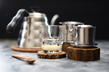Condensed milk in glass ready for making Vietnamese drip coffee in phin on dark background