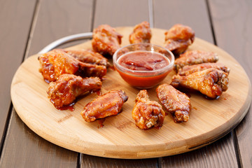 Spicy deep fried chicken wings and legs with dipping sauce on wooden plate , wood background.