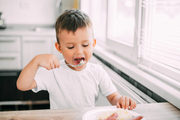 child in the kitchen eating sausage and mashed potatoes