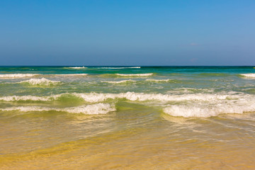 Beautiful blue and green sea water with sand, waves and foam
