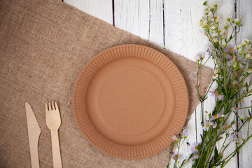 ecological disposable tableware paper cardboard empty on a wooden white table with yellow flowers