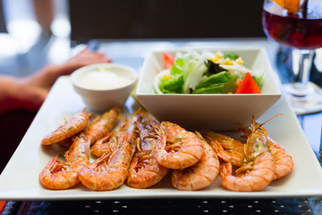 Seafood with king prawns, sauce and salad on a white plate