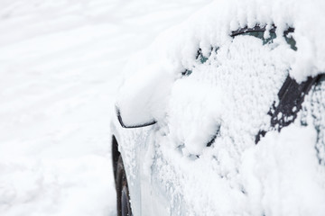 Automobile on parking covered with snow. Parts of a car covered with a layers of snow in the winter. 