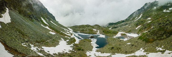 Panoramic view of mountain lake and snow surrounding it
