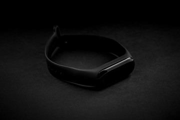 black electronic watch and smart fitness tracker at textured black background. dark object at dark background. dark luxury mood. fashionable accessory.