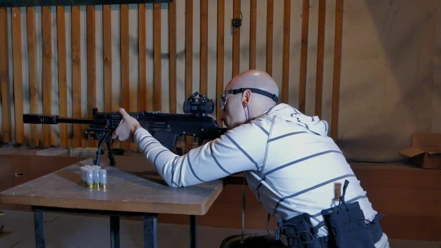 The shooter fires from a large-caliber semi-automatic carbine in a closed shooting range