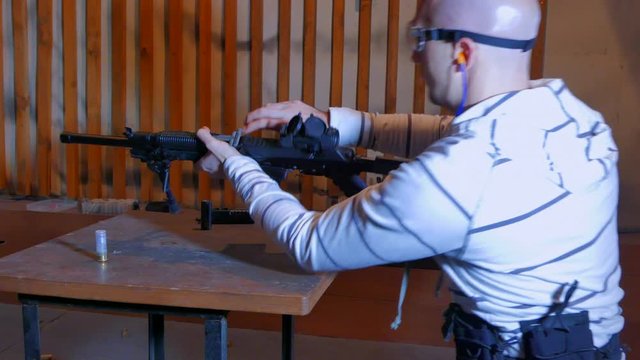 Shooter-man loading a twelve-gauge shotgun. A man trains in target shooting in an indoor shooting range using a high-caliber semi-automatic carbine Vepr-12.