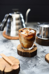 Vietnamese coconut iced coffee in glass served on wood slab on dark background