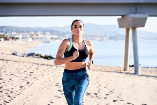 Focused sportswoman running on seashore