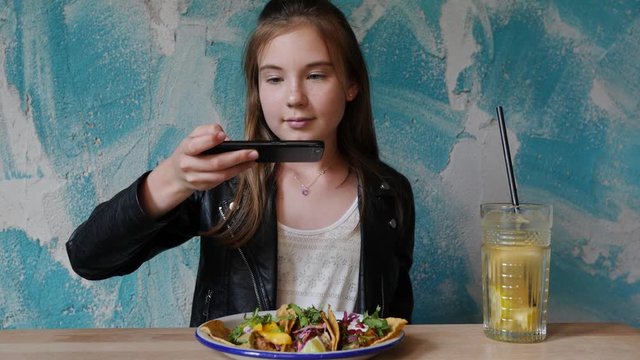 Teenager cute girl in mexican restaurant take smartphone picture food photo for social media having fun before eating