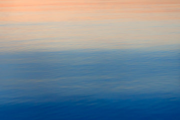 Water surface for background or texture. Sea on sunset. Colorful ripples of the ocean