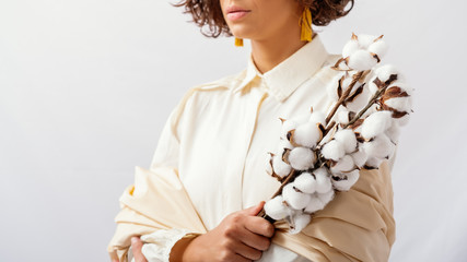 Close Up Of Model Wearing Natural Fabrics And Holding A Cotton Branch