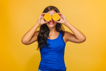 Girl on yellow background closes her eyes with oranges