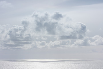 Fluffy grey clouds above a silver sea.