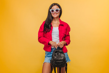 Girl on yellow background in red jacket with backpack