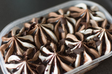 Chocolate and white ice cream on gray table background. Huge container with icecream top view. Copy space.