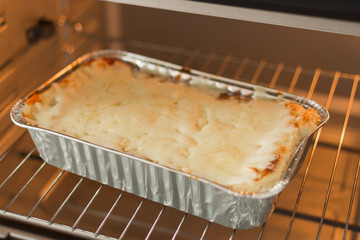 Cheese lasagna in a baking tray in the oven close-up. Process of baking lasagna. Cooking Italian...