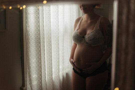 A young pregnant woman looking at her reflection in the mirror