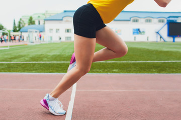 Cropped shot of young female athlete launching off the start line in a race. Female runner started the sprint from the starting line with bright sunlight.