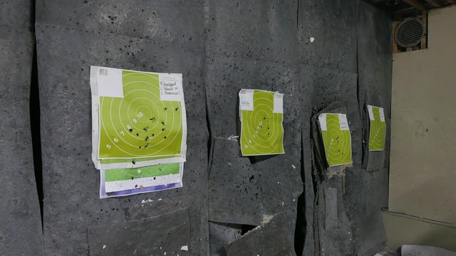 Shooter-man hangs new paper targets in the shooting range.