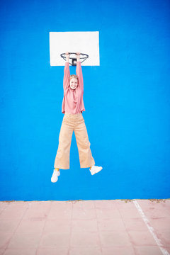 Funny girl in casual clothes hanging on hoop.