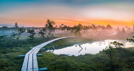 Warmly colored sunrise over a foggy swamp. Aerial view of stunning landscape at peat bog at Kemeri...