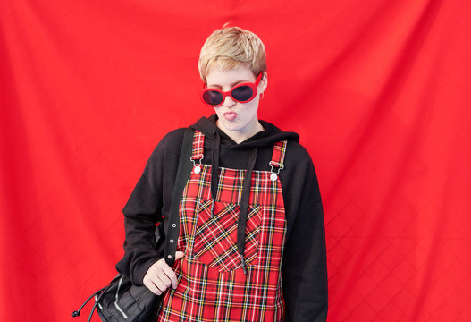 Hipster girl with pouting lips over red background.