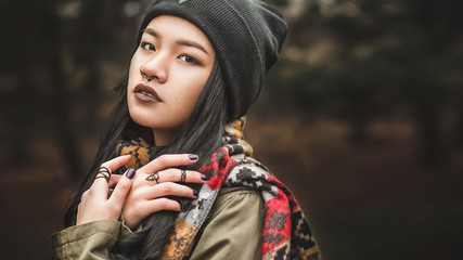 Beautiful woman of Asian appearance drama looks at the camera on a background field. Image close-up / average plan. Bright girl on a dark background.