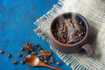 still life with a clay cup filled with coffee beans,anise stars and wooden spoon