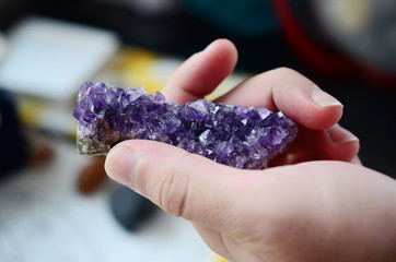 Amethyst crystal cluster being held in woman's hand, lush purple healing crystal cluster. Macro photo in natural lighting, deep purple healing crystal. Natural minerals, crisp colors. 