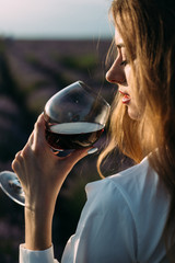 Closeup of girl's face, a glass of red wine in a female hand