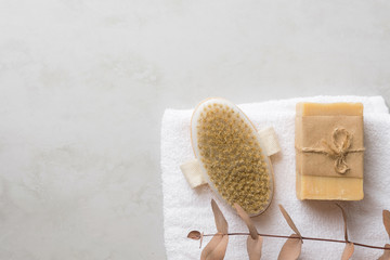 Natural body brush artisan Marseille soap on white pure cotton terry towel on gray marble stone background. Spa wellness skin care organic cosmetics concept