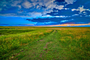 Obraz premium Path in a field with sunset on horizon.