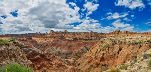Panorama of formations with partly cloudy skies at Badlands National Park.